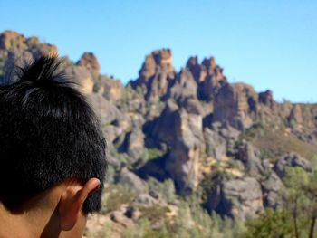 Rear view of man on rock against sky