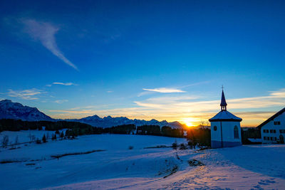 Church by buildings against blue sky during winter