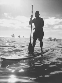 Silhouette man standing on sea against sky