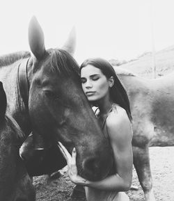 Woman standing by horse against clear sky