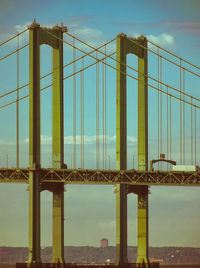 Suspension bridge in city against sky