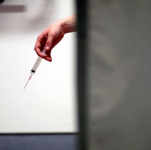 Hand holding syringe with needle