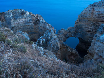 Rock formations in sea against blue sky