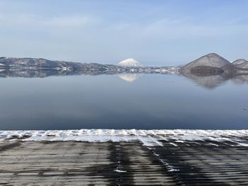 Scenic view of lake by snowcapped mountains against sky