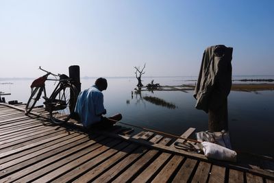 Man fishing at lake against clear sky