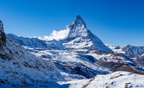 Scenic view of snowcapped mountains against clear blue sky