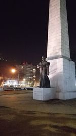 Statue in city against sky at night