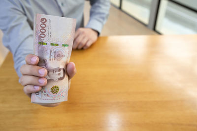 Midsection of woman holding coffee cup on table