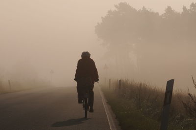 Rear view of man walking on road against sky