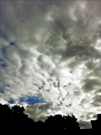 Low angle view of silhouette trees against cloudy sky