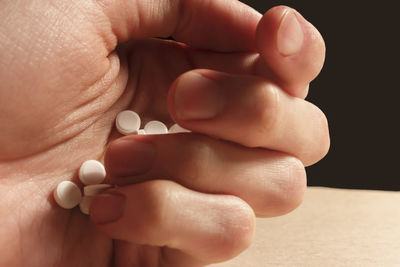 Close-up of hand holding pills on table 