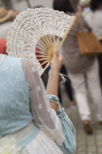 Midsection of woman holding hand fan