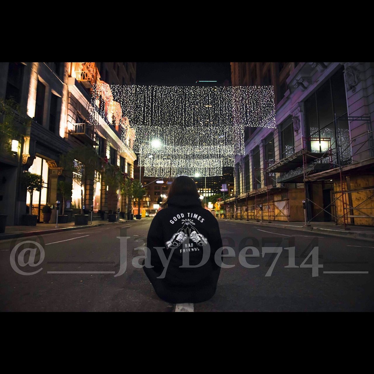 MAN SITTING ON STREET IN CITY AGAINST SKY