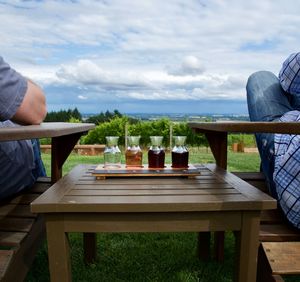 People sitting on chair by table against sky