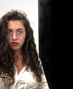 Portrait of beautiful woman standing against curtain