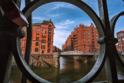 Bridge over canal by buildings against sky