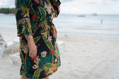 Midsection of woman standing at sandy beach