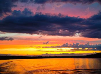 Scenic view of lake against dramatic sky during sunset