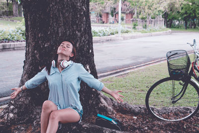 Woman sitting by tree trunk