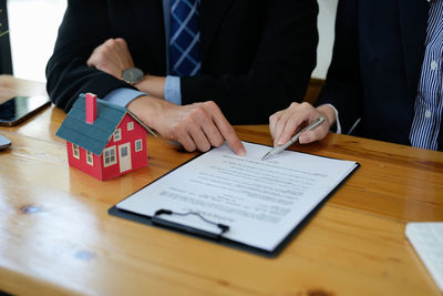 Midsection of man signing document sitting by agent