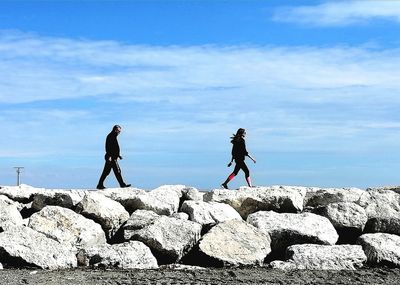 People on rock against sky