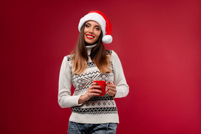 Portrait of a smiling young woman against red background