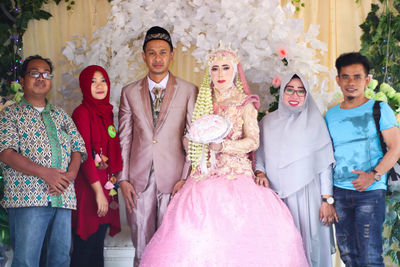 Happy friends standing with couple during wedding ceremony