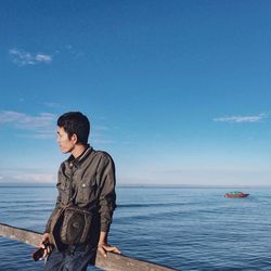 Man leaning on railing against sea