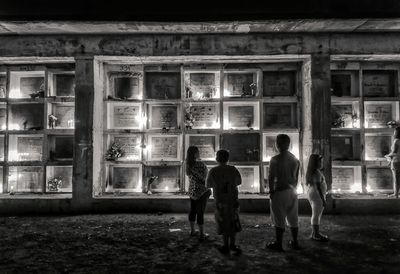 Rear view of people walking on building at night