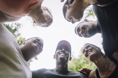 Directly below view of smiling male and female friends huddling at park