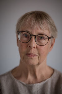 Close-up portrait of old woman against gray background