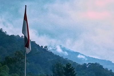 Low angle view of flag on mountain against sky