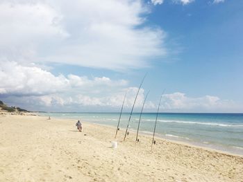 Fishing rods on shore against sky at beach