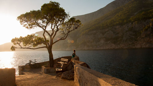 People sitting on mountain by sea against sky