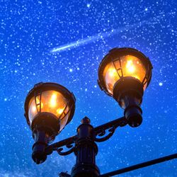 Low angle view of illuminated street light against star field
