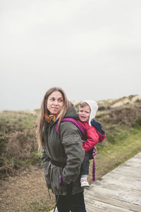 Mother carrying daughter while hiking on mountain