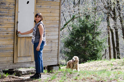 Portrait of woman with dog standing against trees