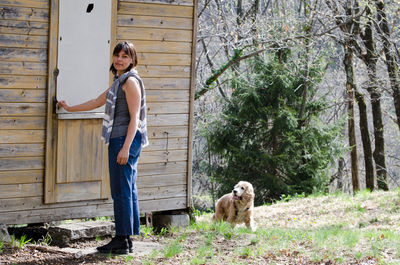 Portrait of woman with dog standing by house door