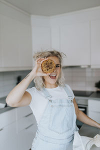 Smiling woman in kitchen holding cookie