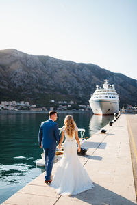 Rear view of couple walking on mountain against sky