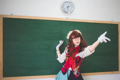 Portrait of young woman standing against wall