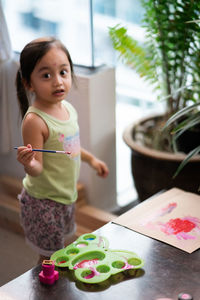 High angle portrait of girl painting on paper