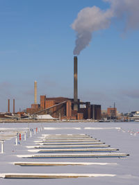 Smoke emitting from coal power plant against bright blue sky