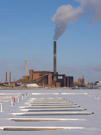 Smoke emitting from factory against sky