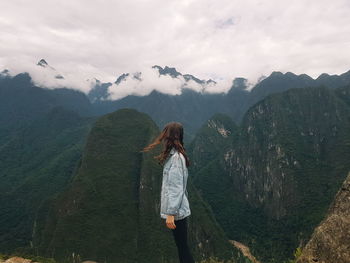 Side view of woman standing against mountains