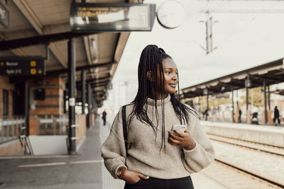 Portrait of young woman standing on railroad station