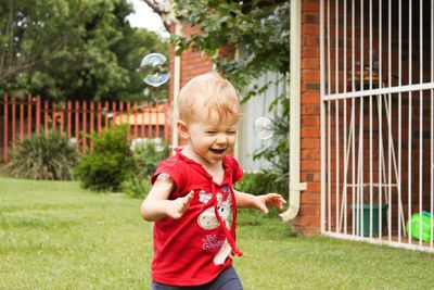 Baby girl playing with bubbles in lawn