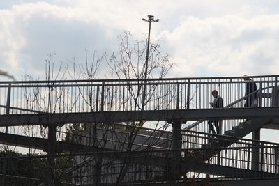 Low angle view of railing against cloudy sky