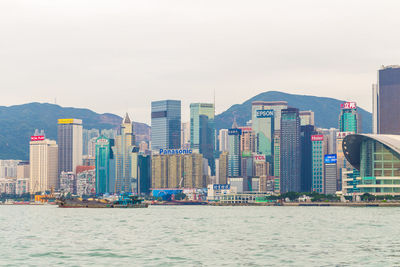 Sea by modern buildings against sky in city