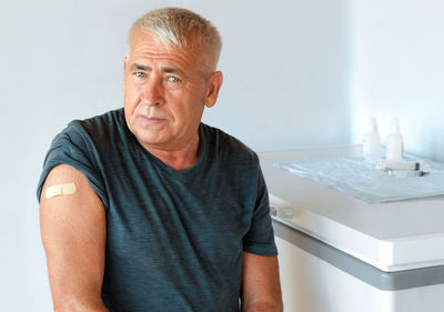 Old man smiling after covid-19 coronavirus vaccine.  senior man showing her arm with bandage, patch.